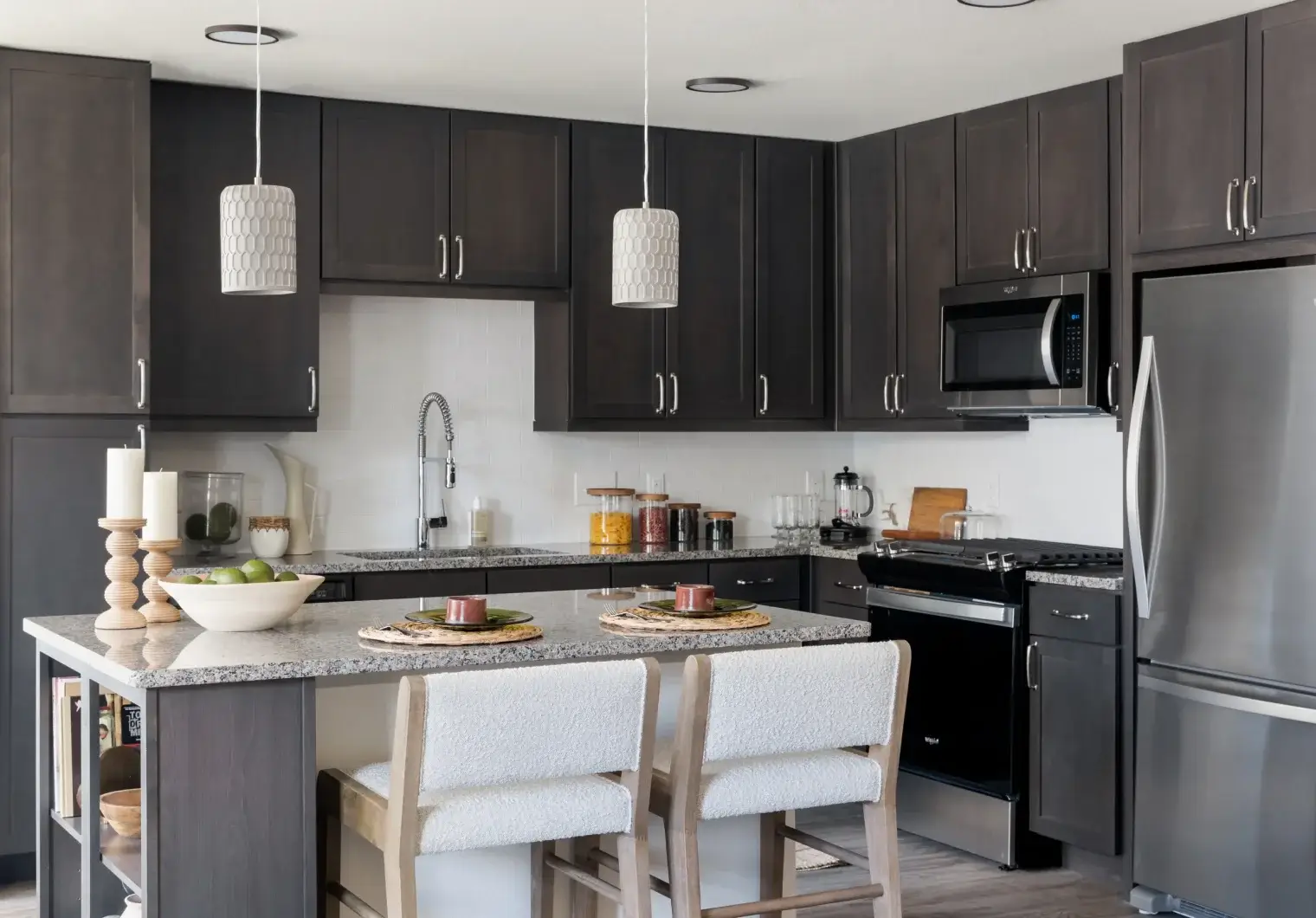 Chef-inspired Six Pines kitchen with dark cabinetry, granite island, and stainless-steel appliances
