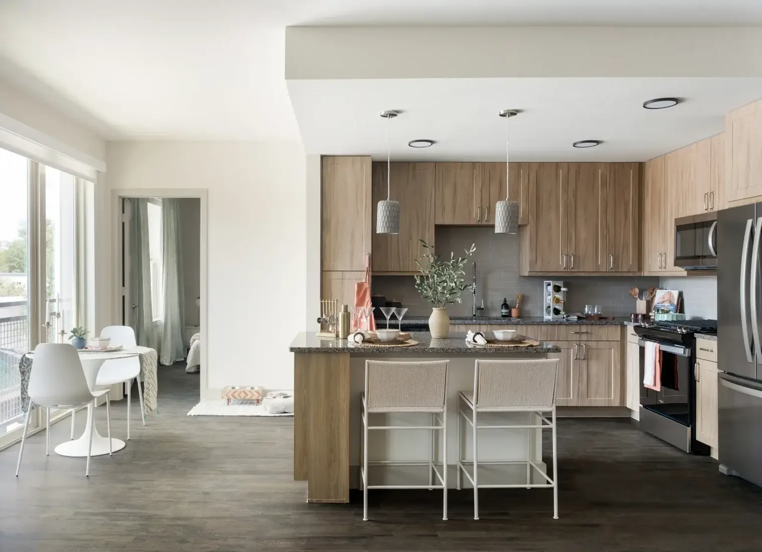 Six Pines apartment kitchen with light cabinetry, island seating, and stainless-steel appliances