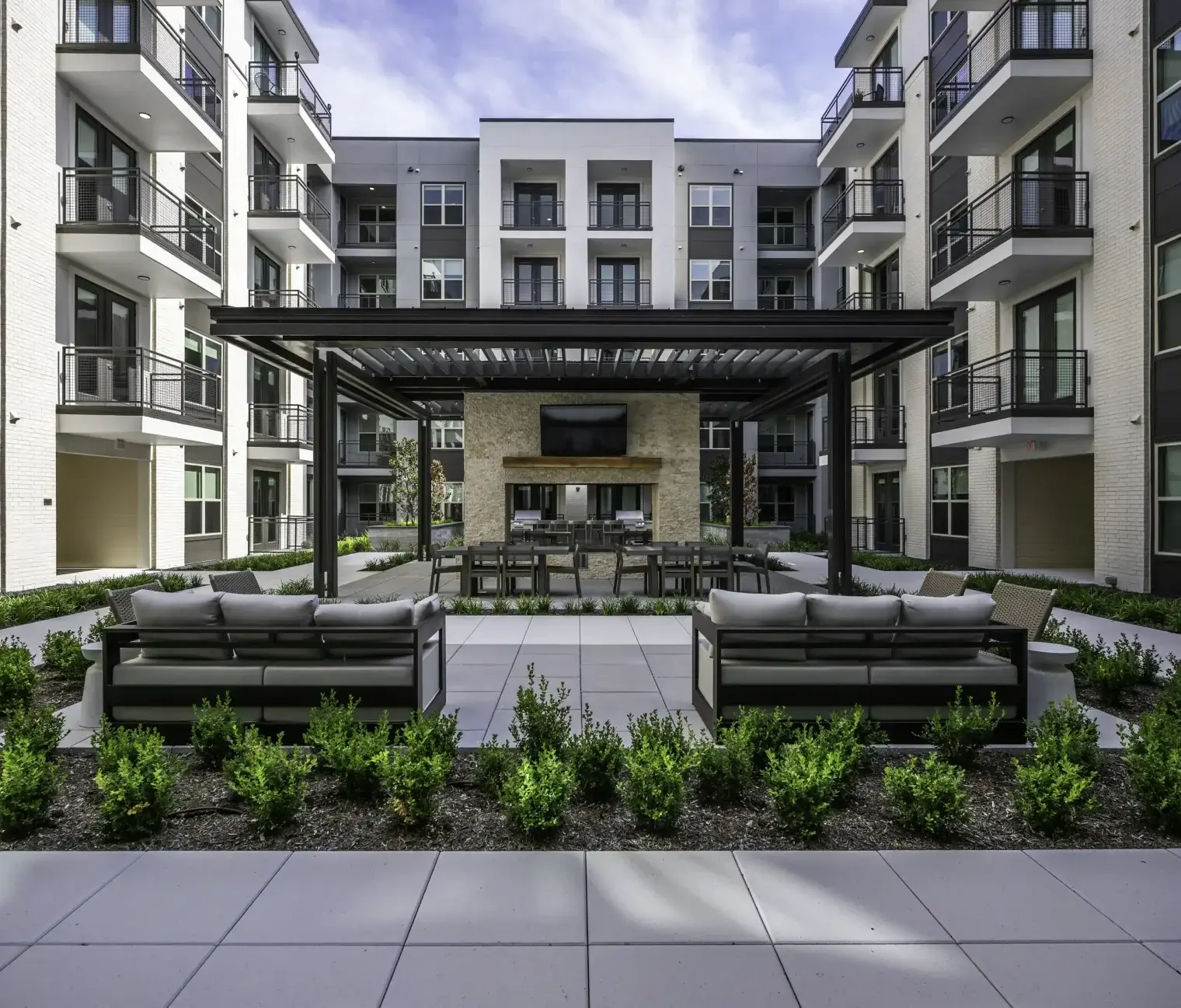 Landscaped courtyard with covered outdoor lounge and entertainment area at Six Pines apartments